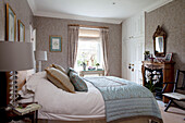 Light blue quilt on bed in Surrey farmhouse with carved wooden fireplace, England, UK