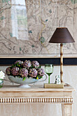 Artichokes and lamp with map and console in living room of Sussex country house, England, UK