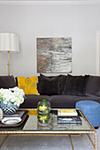 Art canvas and standard lamp with glass topped coffee table in living room of London apartment, UK