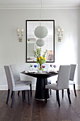 Dining table with mirror reflecting large ceiling light in London apartment, UK