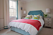 Colourful bedroom with sash window in London townhouse, England, UK