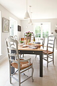 Dining table with wicker seated chairs in contemporary Maidstone farmhouse, Kent, England, UK