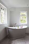 Freestanding bath below windows in corner of room, Maidstone farmhouse, Kent, England, UK