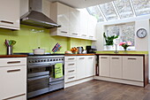 Lime green splashback in cream fitted kitchen of contemporary London townhouse, England, UK