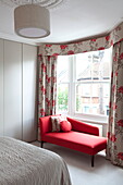 Red chaise longue at curtained bedroom window of contemporary London townhouse, England, UK