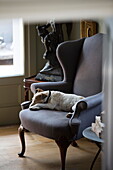 Dog sleeping on upholstered wingback armchair in historic Sussex country home England UK