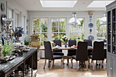 Dining table and sideboard in conservatory extension of historic Sussex country home England UK