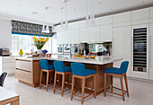Blue barstools at breakfast bar in spacious kitchen of Surrey country home England UK