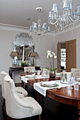 Antique dining table with cut glass chandeliers in contemporary Surrey country home England UK