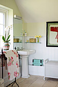 Floral bath towel beside pedestal basin in tiled bathroom of Sussex home England UK