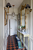 Gilt-framed mirrors in terracotta hallway with console in Wells next the Sea, Norfolk, England, UK