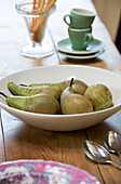 Pears in bowl with espresso cups in Dorset cottage kitchen, England, UK