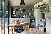 Schwarze Stühle am hölzernen Küchentisch in einem modernisierten bretonischen Landhaus in Westfrankreich