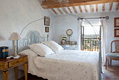 Double bed with twisted metal frame and open window to Mougins landscape in Alpes-Maritime, South of France