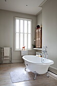Freestanding roll-top bath with shuttered window in London townhouse, England, UK