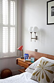 Leaf motif cushion with vintage light fitting in bedroom of London townhouse, England, UK