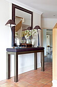 Dark wood console table with mirror and matching lamps in hallway of Kent home, England, UK