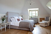 Light grey quilt and headboard on bed in room with wooden floor, Kent home, England, UK