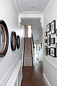 Convex mirrors and artwork in white hallway of London townhouse England UK