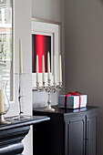 Silver candelabra and gift-wrapped present on black cabinet in London townhouse England UK
