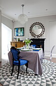 Blaue und Ghost-Esszimmerstühle am Tisch auf gemustertem Teppich in einem Londoner Stadthaus England UK