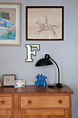 Buchstabe 'F' und Kunstwerk mit schwarzer Lampe auf hölzernem Sideboard in Familienhaus in Kent England UK