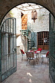 View through wrought iron gates to courtyard dining area of French holiday villa