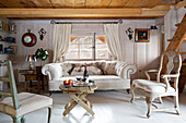 Cream sofa and chairs with wooden table in living room of mountain chalet in Chateau-d'Oex, Vaud, Switzerland