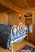 White wrought iron bed in wood panelled room, mountain chalet, Chateau-d'Oex, Vaud, Switzerland