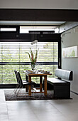 Leather bench seat and chairs at dining table in window of contemporary SW London home, England, UK