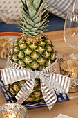 Pineapple tied with bow on dining table in Chilterns home, England, UK