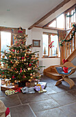 Christmas tree and wooden chair in flagstone staircase hallway of Chilterns home England UK