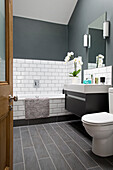 Orchid on washbasin in white tiled bathroom of contemporary Brighton home, East Sussex, England, UK