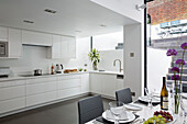 Cut flowers in white basement kitchen of contemporary Brighton home East Sussex England UK