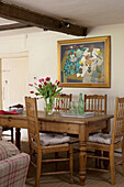 Cut tulips on wooden dining table with gilt-framed artwork in Burwash home East Sussex England UK
