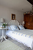 Toile de jouy cushions and checked cover on bed with cut roses at beside in West Sussex home, England, UK