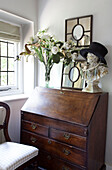 Mirror and bust on antique writing desk at window in West Sussex home, England, UK
