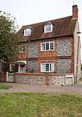 Three storey pebble dash and brick exterior of West Sussex detached home, England, UK