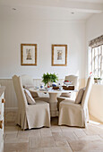 Cream slip-covered dining chairs at table in West Mailing home Kent England UK