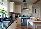Saucepans on light blue range oven in cream fitted kitchen in London home England UK