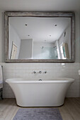 Freistehende Badewanne unter einem großen Spiegel in einem Londoner Stadthaus, England, UK