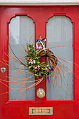 Christmas garland on bright red front door of London home, England, UK