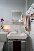 Towel hooks above washbasin with marble surround in grey bathroom of London home, England, UK