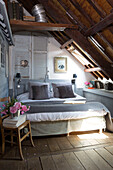 Cut flowers on wooden chair at foot of bed in French farmhouse