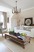 White sofa with large clock and low wooden coffee table in Twickenham townhouse, Middlesex, England, UK