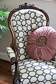 Circular cushion on upholstered armchair in London family home, England, UK