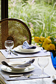Blue gingham napkins on bowls with wicker chair back in Oxfordshire dining room England UK