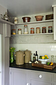 Storage jars on kitchen shelves with citrus fruits in colander in Ceredigion farmhouse Wales UK