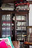 Folded woolen blankets in glass-fronted cabinet in Ceredigion cottage Wales UK