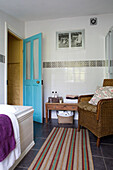 Striped bathmat and wicker chair in tiled bathroom of Ceredigion cottage Wales UK